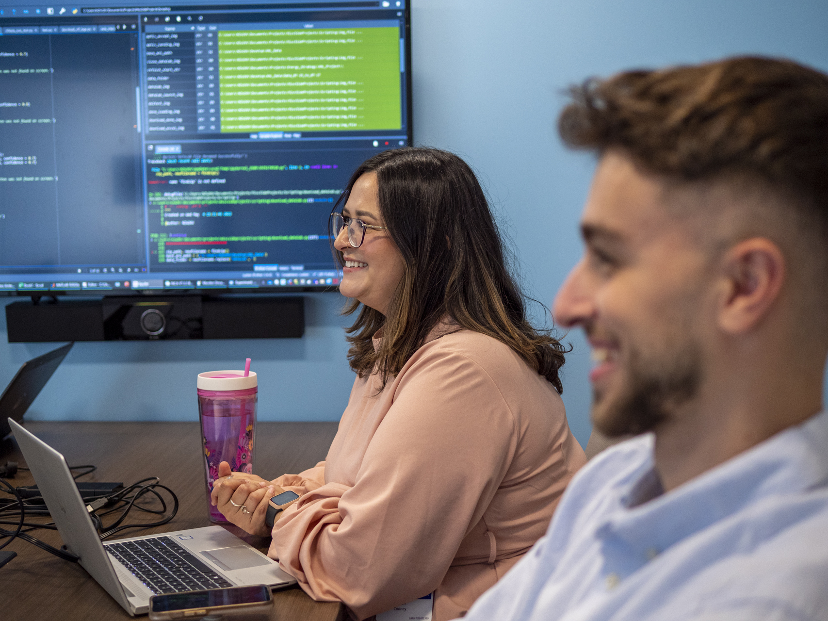Woman in safety glasses smiling in manufacturing plant